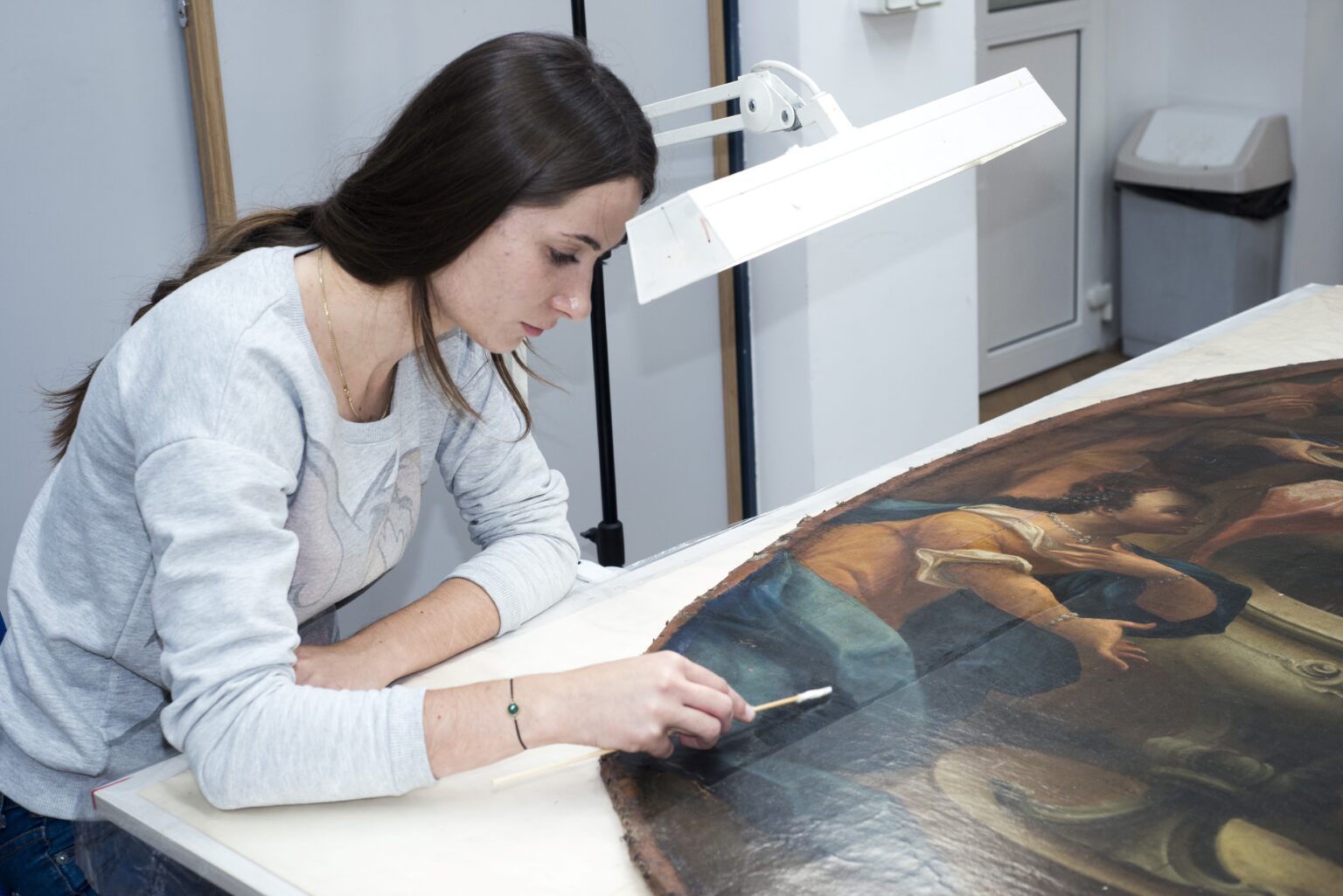 Studentka podczas oczyszczania lica malowidła z wtórnych nawarstwień.