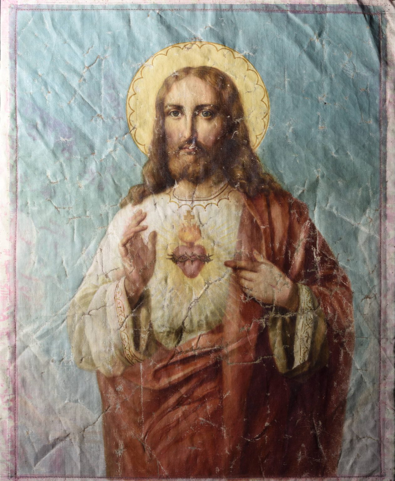 obraz przedstawiający Jezusa z ręką uniesioną w geście błogosławieństwa. Postać z brodą i długimi włosami ubrana w biało czerwone szaty - stan przed konserwacja, światło boczne