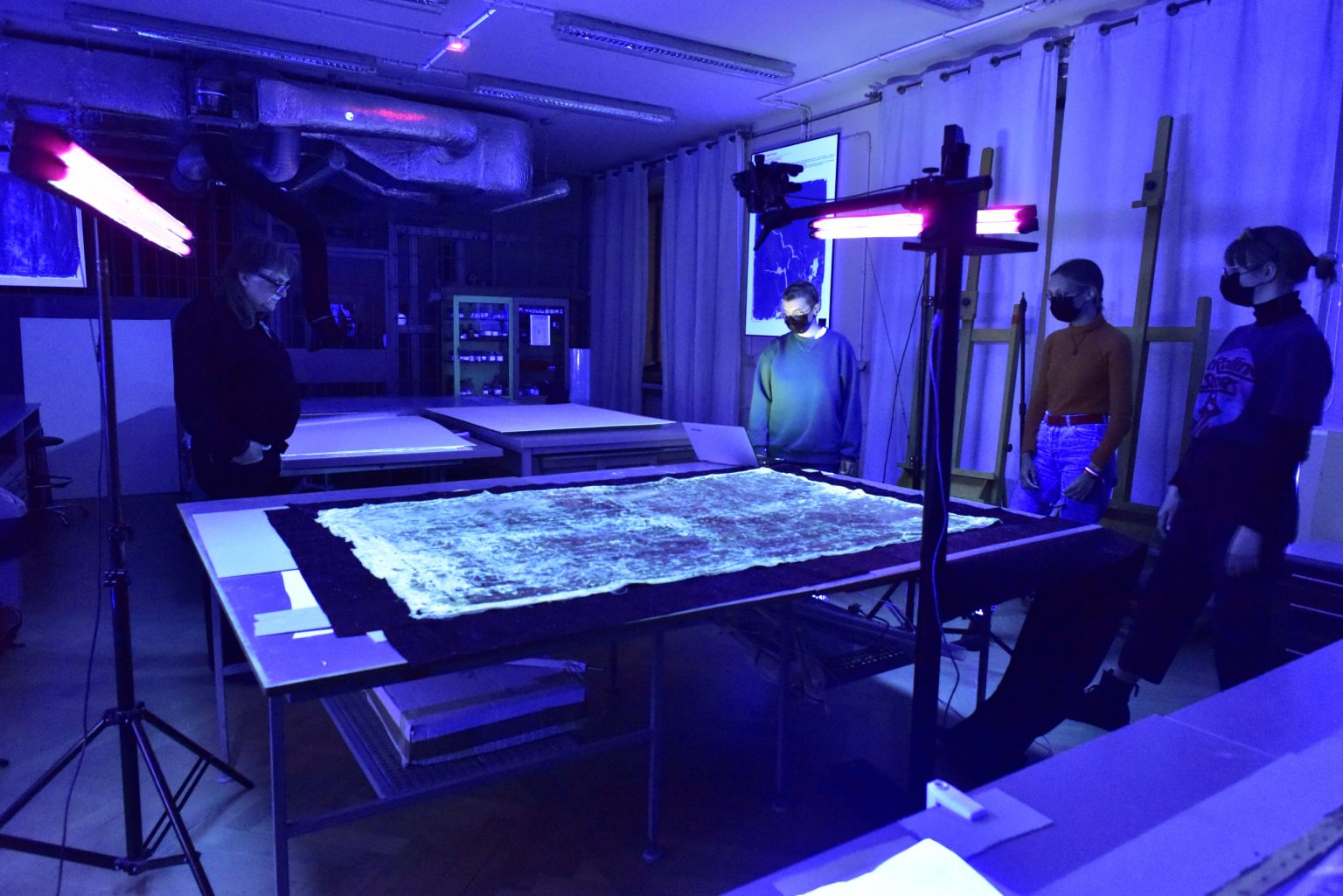 Grupa ludzi wokół rozłożonego na stole rekonstruowanego obrazu