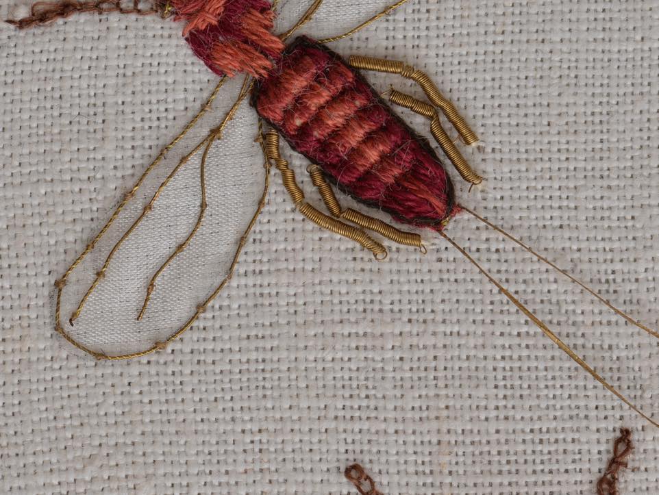 Zbliżenie na haft przedstawiającyczerwonego owada