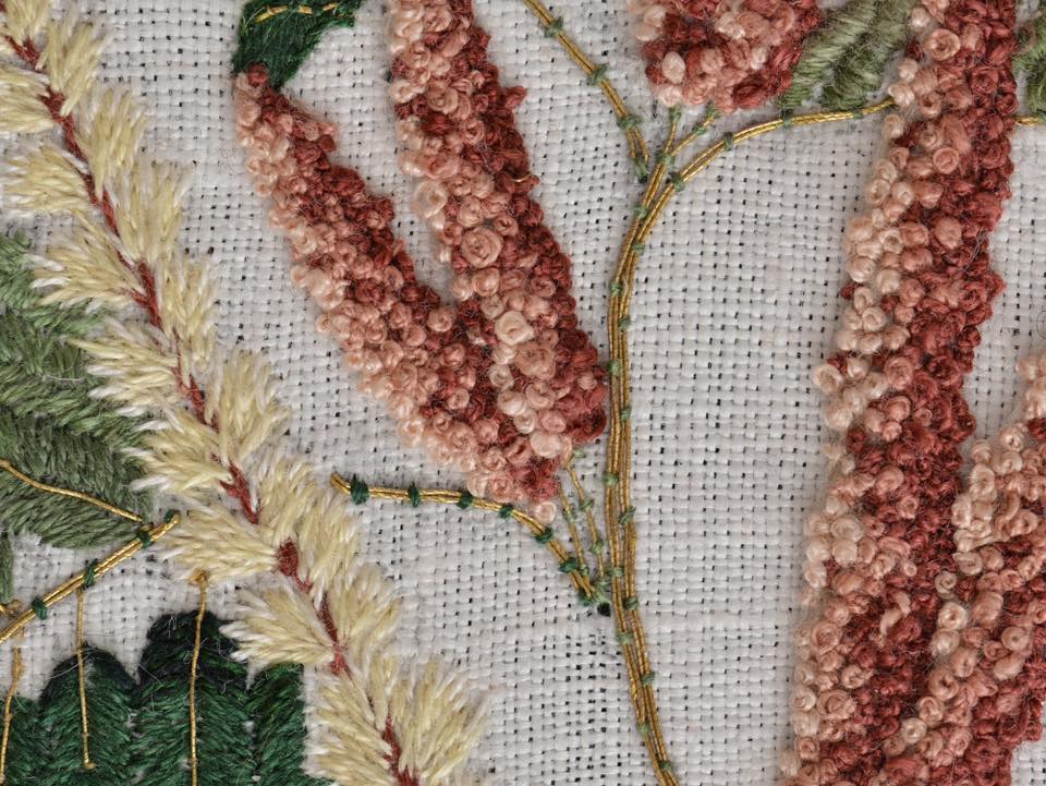 Zbliżenie na haft przedstawiające rośliny w kolorach czerwonym i białym