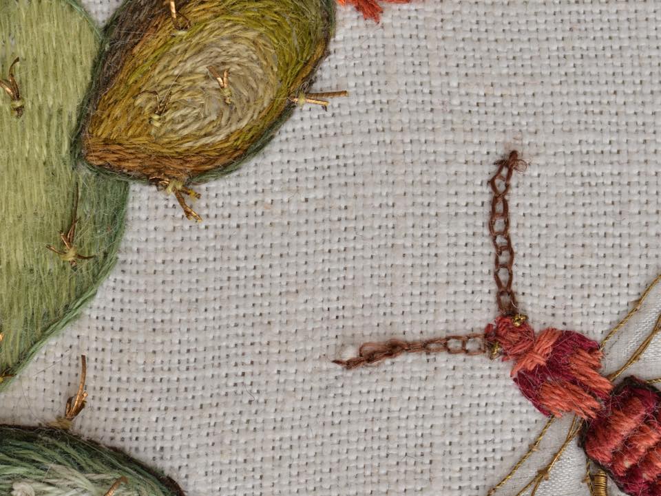 Zbliżenie na haft przedstawiający kaktusa oraz czerwonego owada