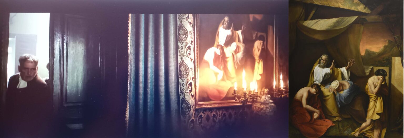 Kadr z filmu, postać mężczyzny przechodzi przez drzwi, po prawej stronie obraz oświetlony świecznikiem