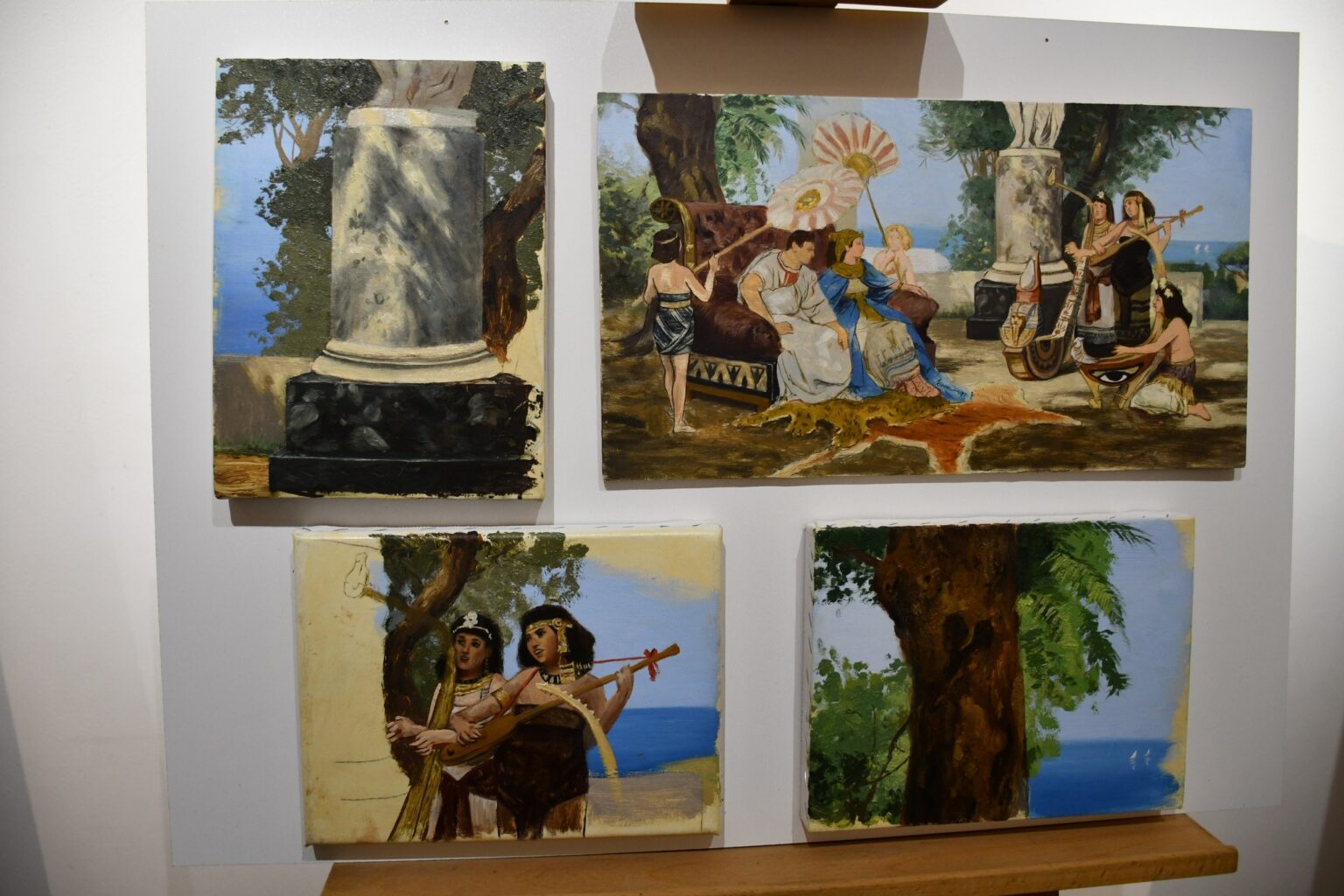 Zestaw czterech szkiców malarskich przedstawionych na białym tle. Każdy szkic ukazuje różne elementy pejzażu lub scen z życia w stylu antycznym, w tym postacie, kolumnę i drzewa.