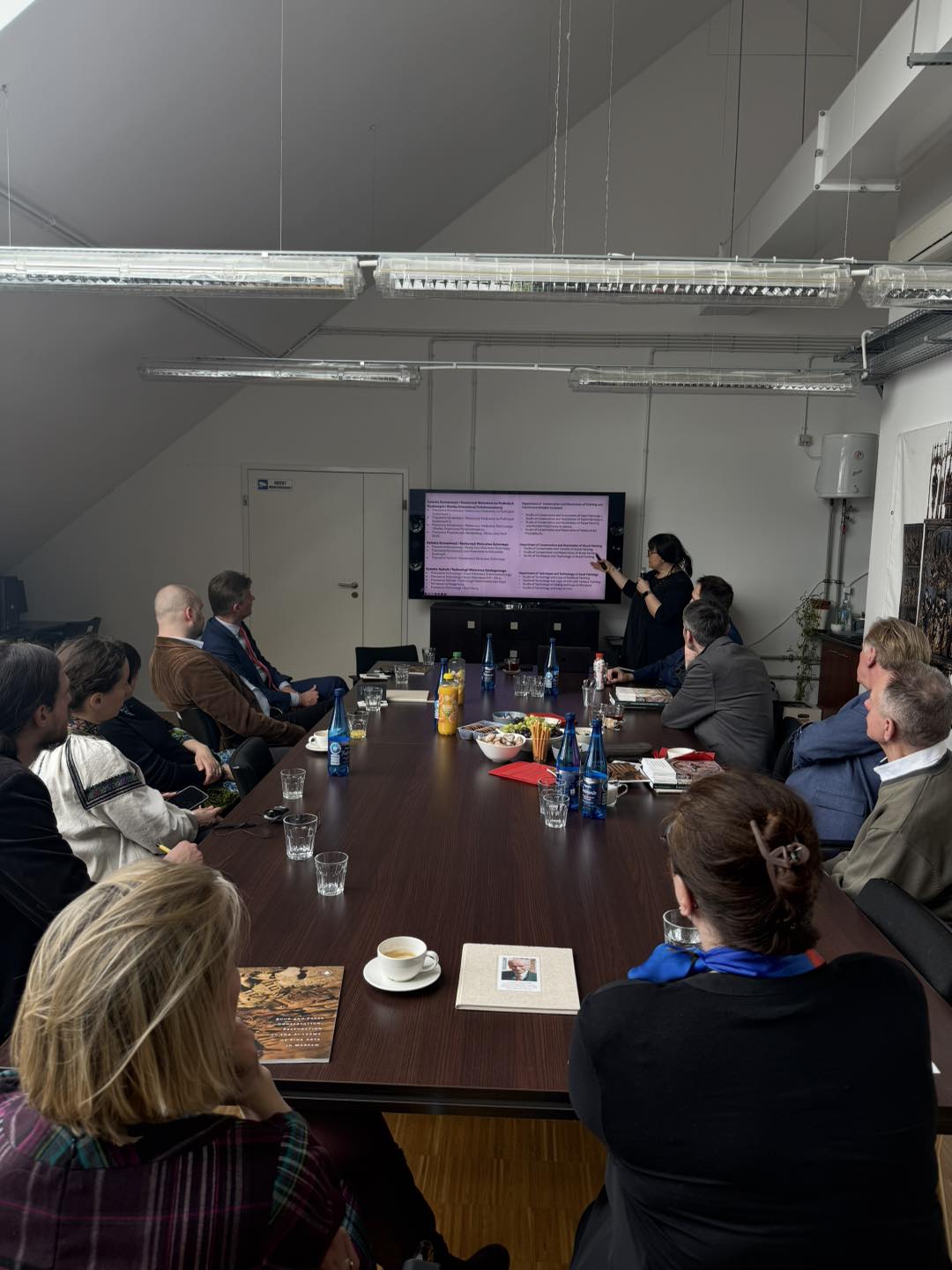 Spotkanie przy stole konferencyjnym, prezentacja na ekranie.