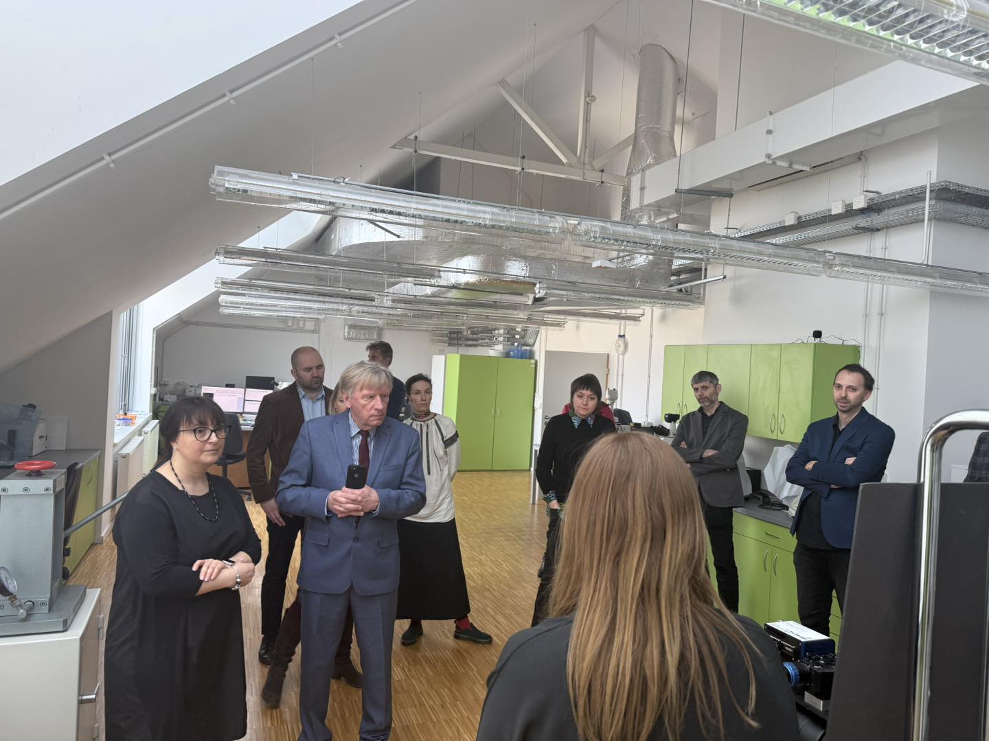 Grupa ludzi w pracowni, prowadzone jest oprowadzanie.