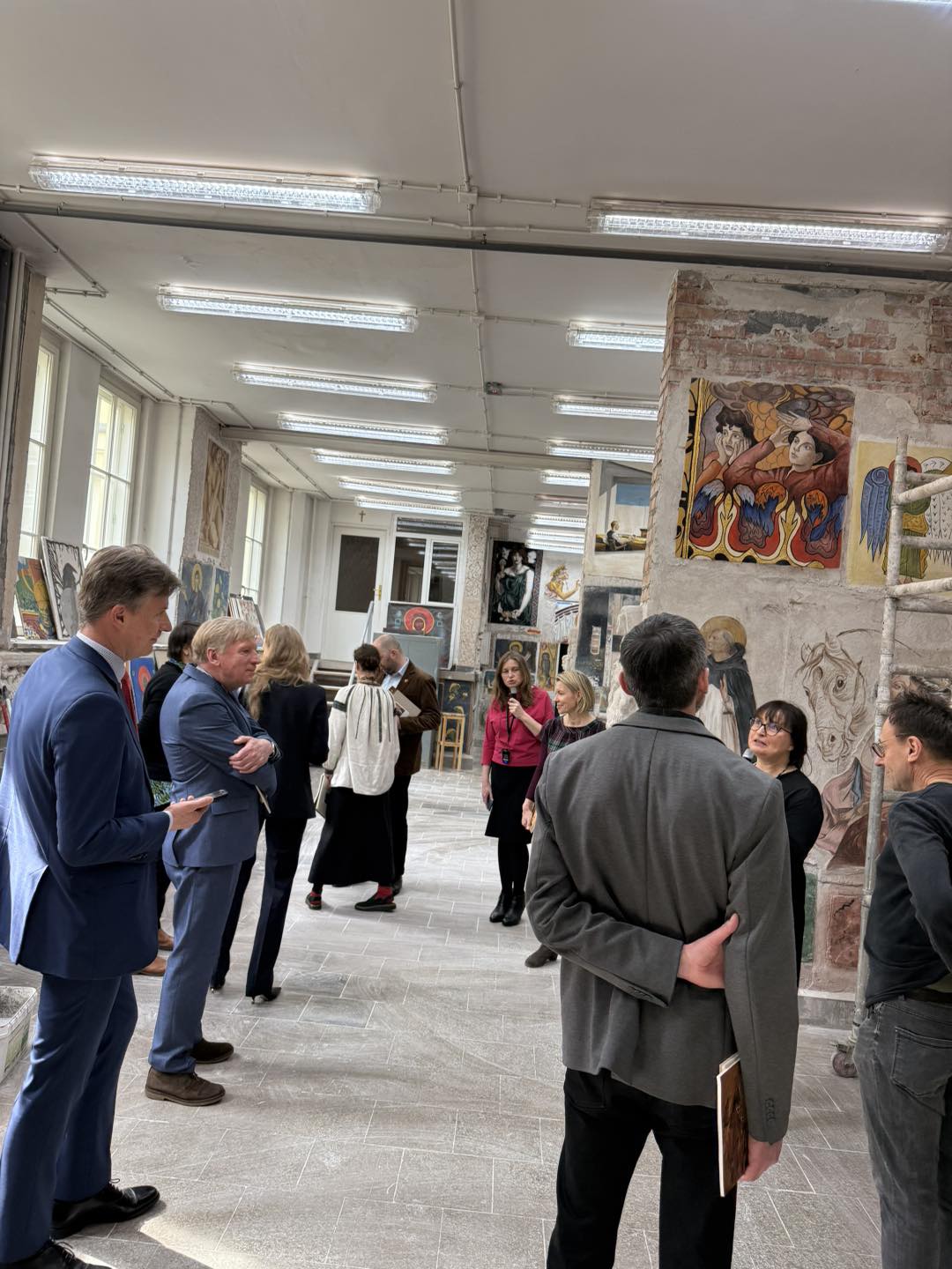 Grupa osób odwróconych tyłem stoi w pracowni