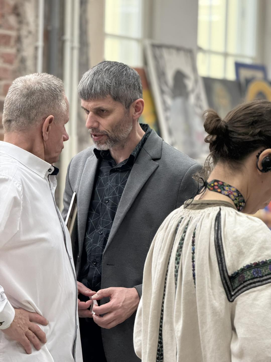 Dwóch mężczyzn rozmawia, obok kobieta w tradycyjnym stroju.