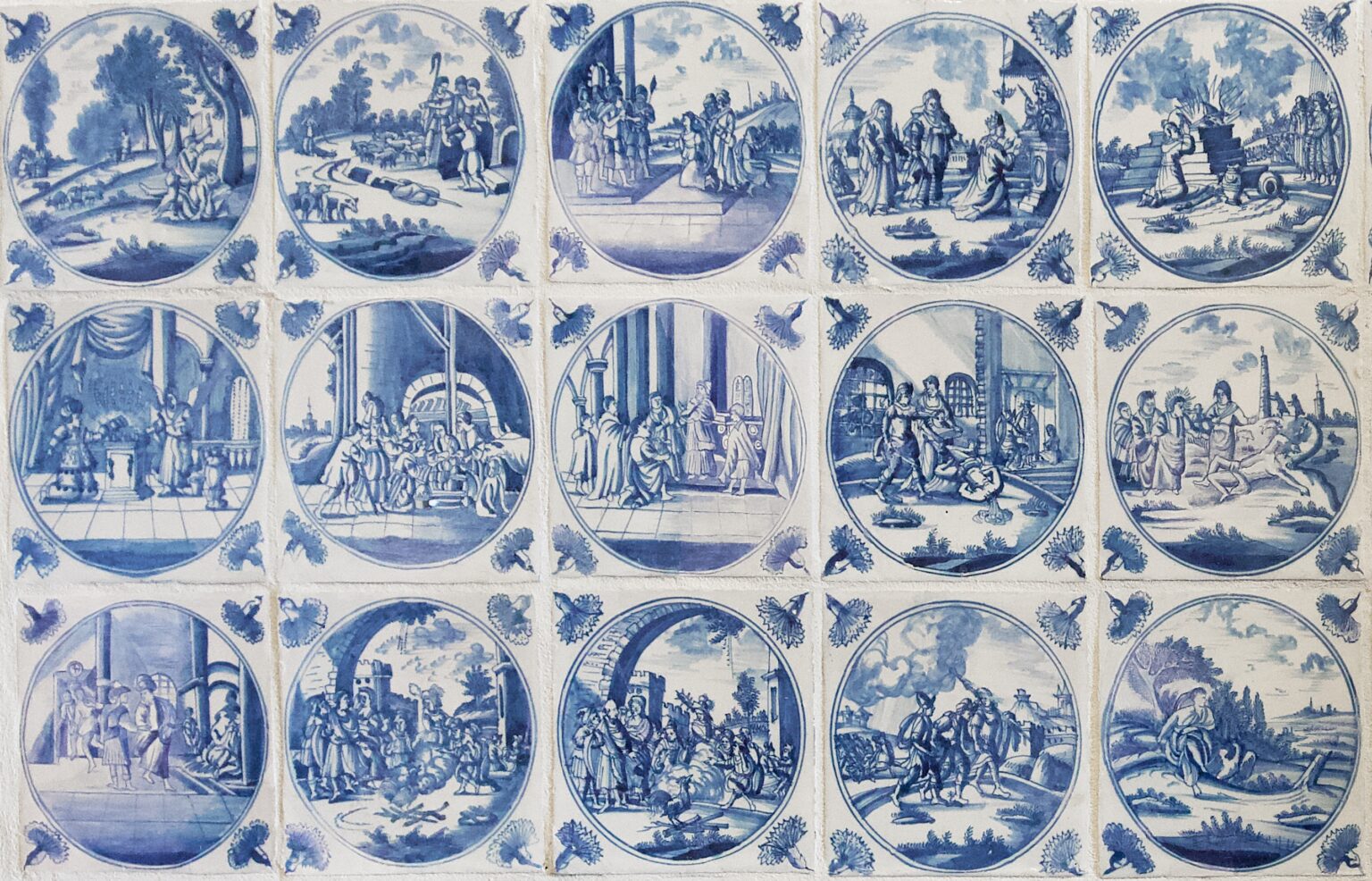 Zbiór dekoracyjnych kafli ceramicznych utrzymanych w odcieniach niebieskiego, przedstawiających sceny biblijne lub mitologiczne w okrągłych medalionach, otoczonych ornamentami roślinnymi.