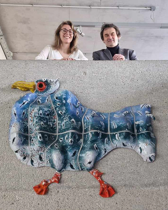 mężczyzna i kobieta stoją na balkonie, pod nimi ceramiczna płaskorzeźba ptaka